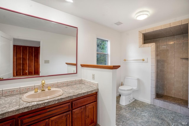 bathroom with tile floors, toilet, a tile shower, and vanity