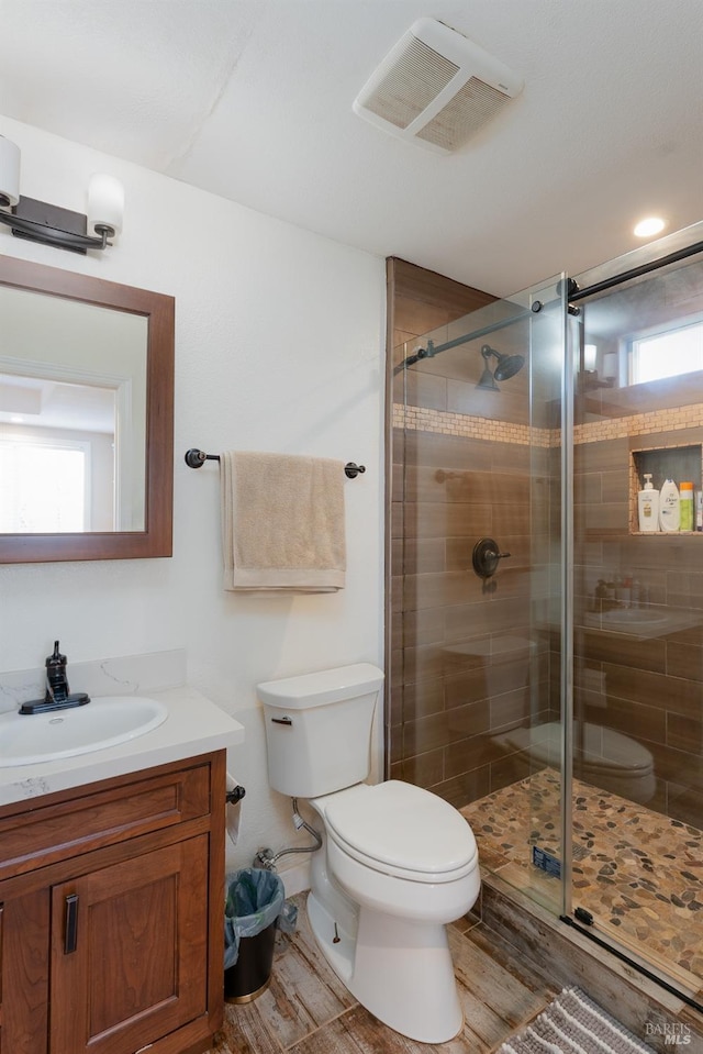 bathroom featuring vanity, walk in shower, and toilet