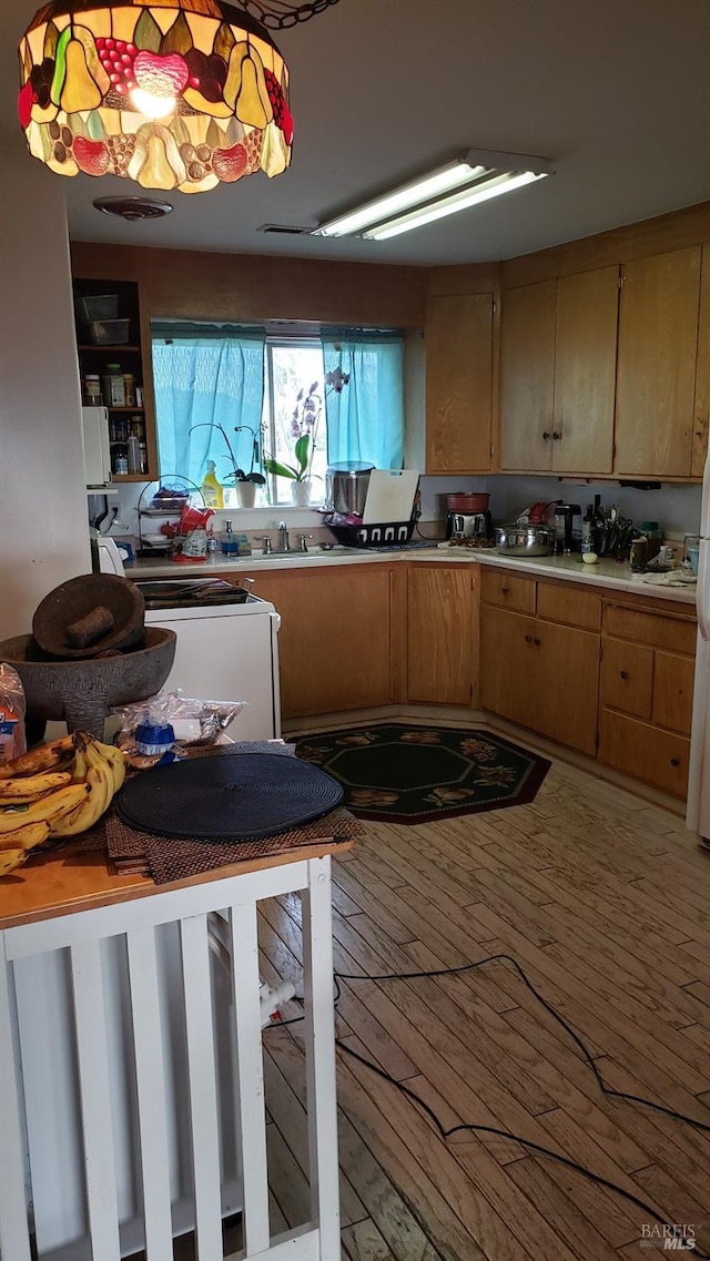 kitchen with white refrigerator, hanging light fixtures, and light hardwood / wood-style flooring