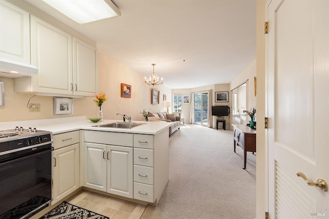 kitchen with kitchen peninsula, decorative light fixtures, black gas range oven, sink, and light carpet