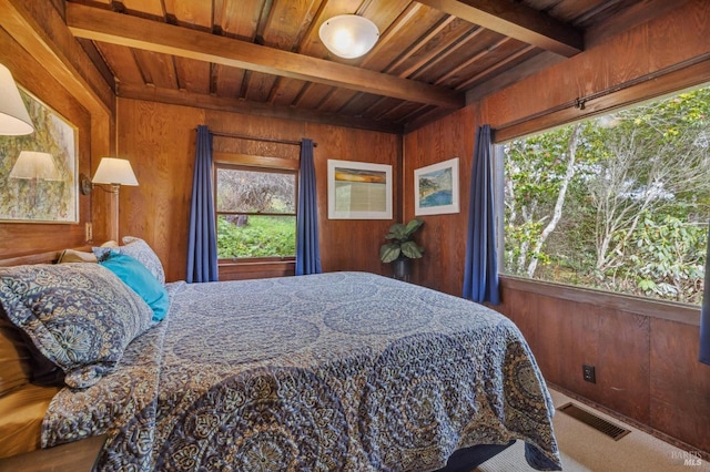 bedroom with multiple windows, wooden walls, wood ceiling, and beam ceiling