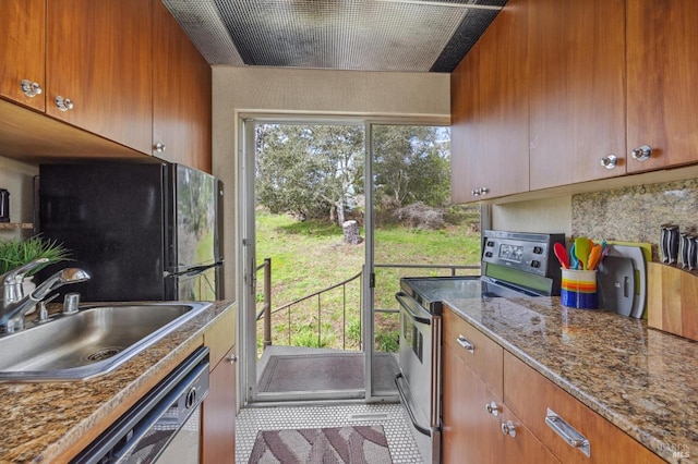 kitchen with light stone counters, sink, tile patterned floors, and stainless steel appliances