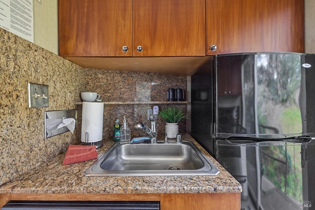 kitchen featuring black refrigerator, sink, and tasteful backsplash