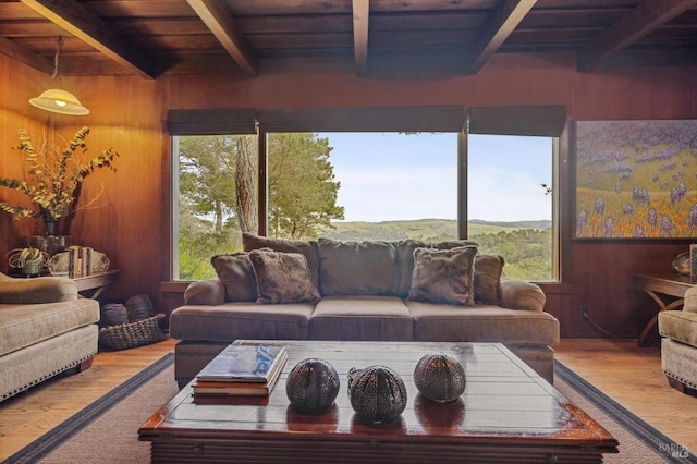 living room featuring hardwood / wood-style flooring, wooden walls, beam ceiling, and wooden ceiling