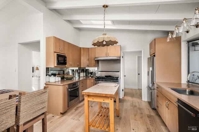 kitchen with under cabinet range hood, a sink, light wood-type flooring, lofted ceiling with beams, and appliances with stainless steel finishes
