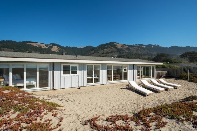 rear view of property with board and batten siding, fence, and a mountain view
