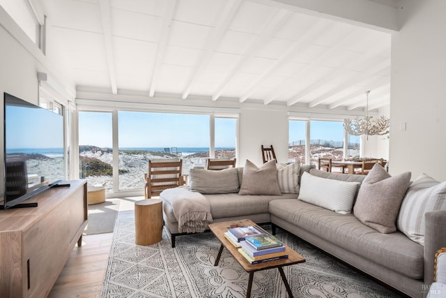 living room with lofted ceiling with beams, a chandelier, light wood-style floors, and a water view