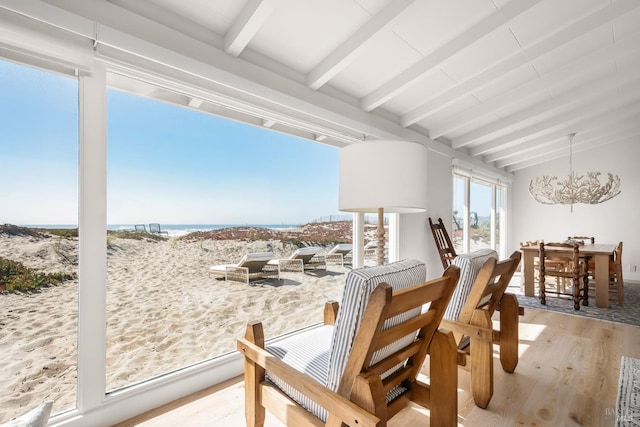 interior space featuring beamed ceiling, a water view, and a notable chandelier