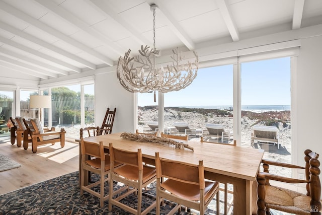 dining area with vaulted ceiling with beams, wood finished floors, and an inviting chandelier