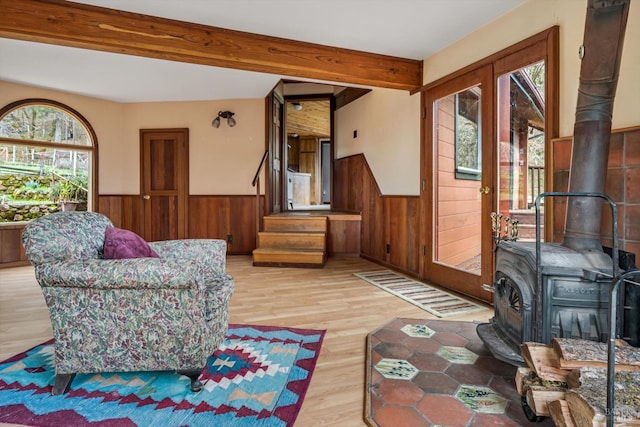 living room featuring beamed ceiling, light hardwood / wood-style floors, and a wood stove