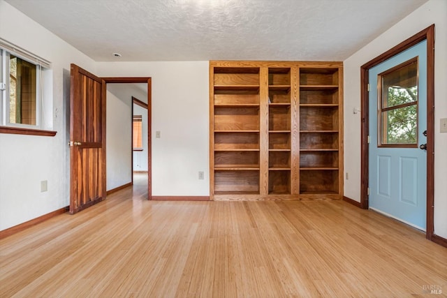 spare room featuring light hardwood / wood-style floors and a textured ceiling