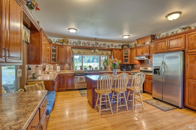 kitchen featuring stainless steel appliances, a kitchen breakfast bar, a center island, light hardwood / wood-style floors, and decorative backsplash