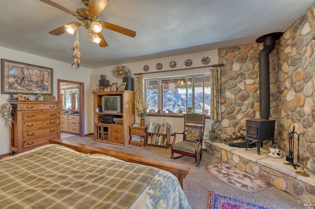 bedroom with carpet floors, ceiling fan, and a wood stove