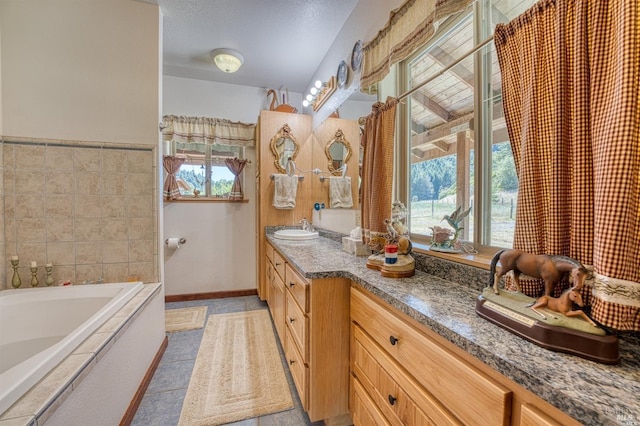 bathroom with vanity, tile patterned flooring, a washtub, and a healthy amount of sunlight