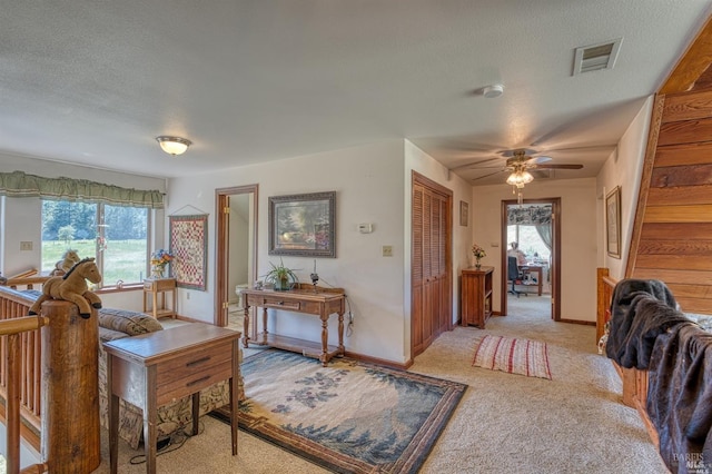 carpeted living room with a textured ceiling and ceiling fan