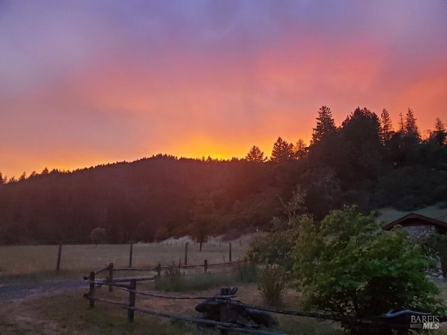 yard at dusk featuring a rural view