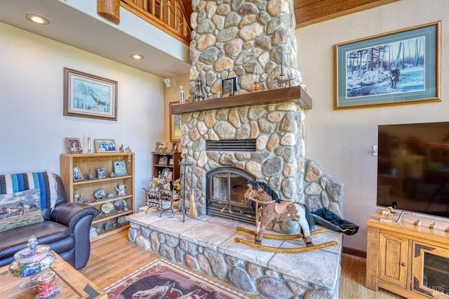 living room with a stone fireplace and light hardwood / wood-style flooring