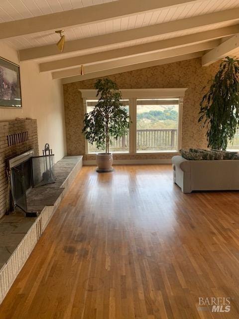 unfurnished living room featuring hardwood / wood-style flooring, vaulted ceiling with beams, and a brick fireplace