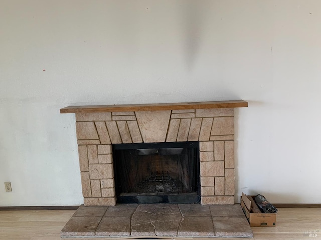 room details with a stone fireplace, wood finished floors, and baseboards