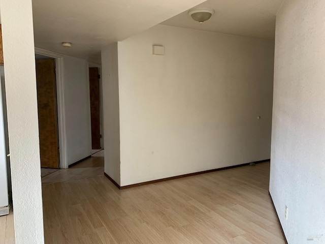 empty room featuring baseboards and light wood finished floors