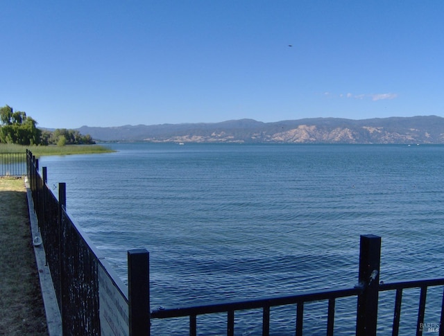 property view of water featuring a mountain view and fence