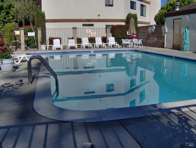 community pool with fence and a patio