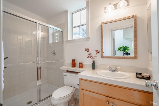 bathroom with oversized vanity, toilet, and a shower with door