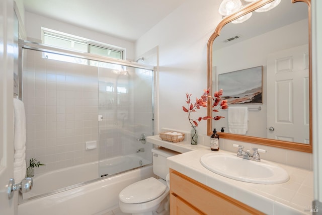 full bathroom featuring toilet, large vanity, and shower / bath combination with glass door