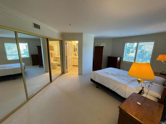 bedroom featuring ensuite bath, crown molding, light carpet, and a closet