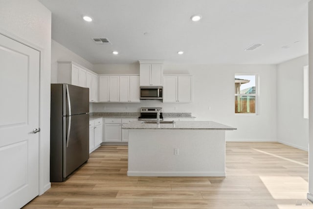 kitchen with white cabinetry, light hardwood / wood-style flooring, an island with sink, and appliances with stainless steel finishes