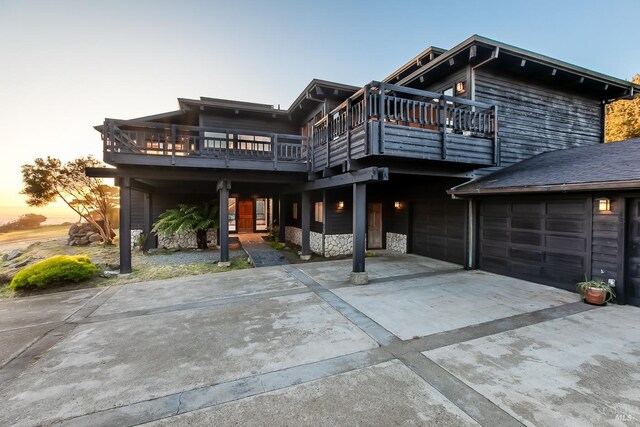 exterior space featuring concrete driveway, stone siding, and an attached garage