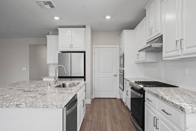 kitchen with hardwood / wood-style floors, light stone countertops, white cabinets, sink, and stainless steel appliances