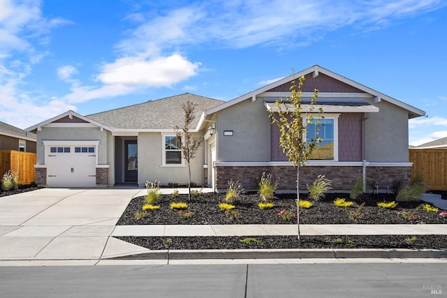 view of front facade with fence, an attached garage, a shingled roof, concrete driveway, and stone siding