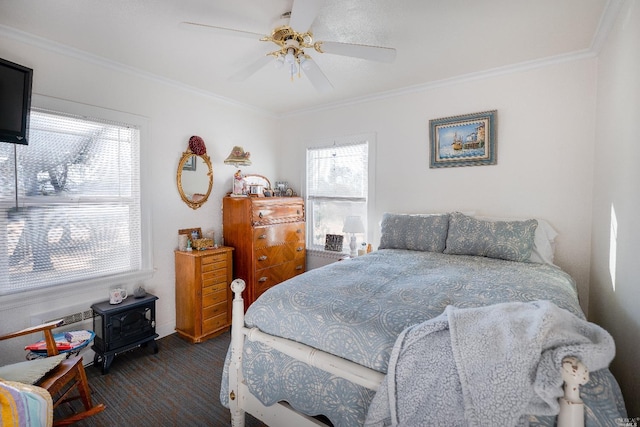 carpeted bedroom with ceiling fan, a wood stove, and ornamental molding