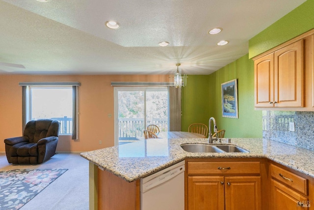 kitchen featuring white dishwasher, a healthy amount of sunlight, light colored carpet, sink, and kitchen peninsula