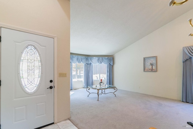 entryway featuring vaulted ceiling, a textured ceiling, and light colored carpet