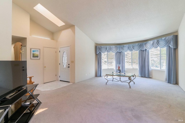 living room with a textured ceiling, light colored carpet, high vaulted ceiling, and a skylight