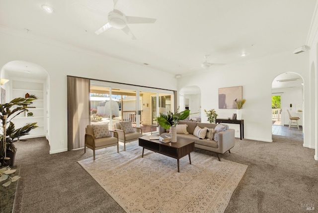 carpeted living room featuring arched walkways, ceiling fan, ornamental molding, and plenty of natural light