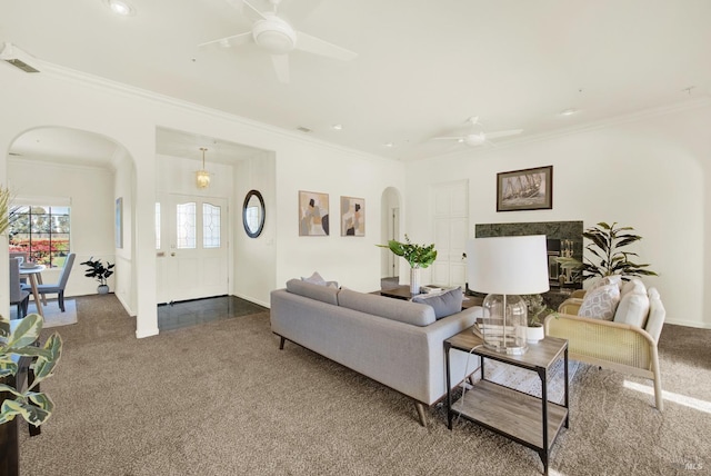 living room featuring a high end fireplace, carpet floors, ceiling fan, and ornamental molding