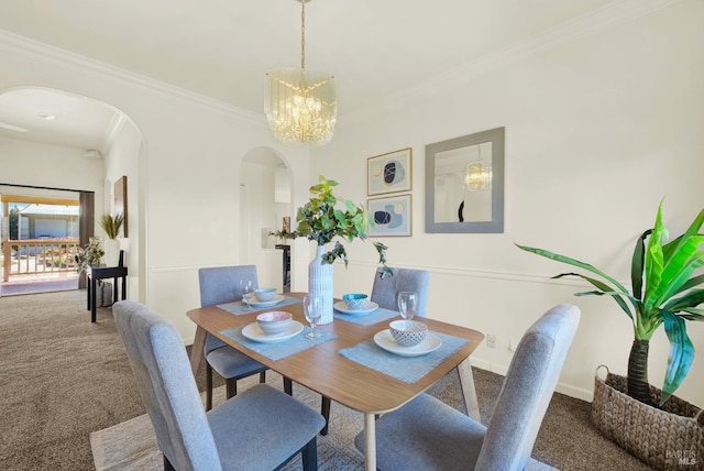 dining space with carpet floors, arched walkways, ornamental molding, and an inviting chandelier