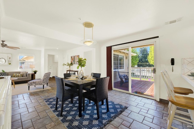 dining space featuring a ceiling fan, stone tile flooring, and visible vents