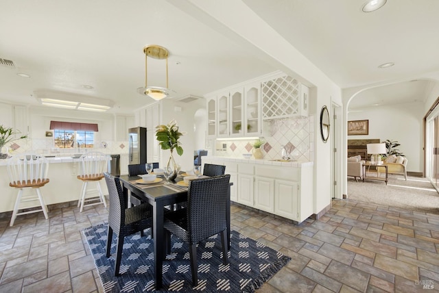 dining room featuring stone tile floors, arched walkways, and recessed lighting