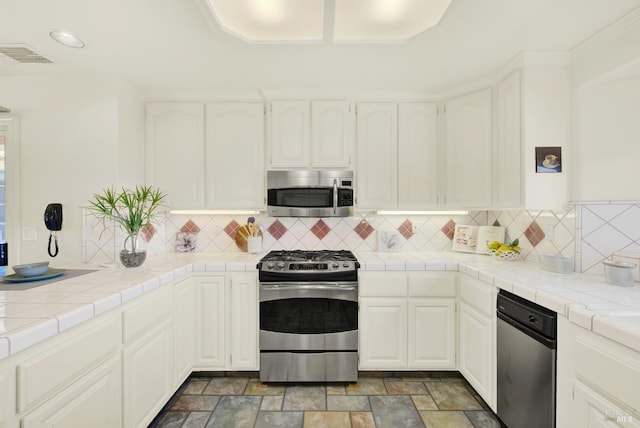 kitchen with white cabinets, appliances with stainless steel finishes, recessed lighting, tasteful backsplash, and visible vents