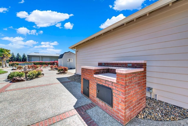 view of patio with an outdoor structure and a storage unit