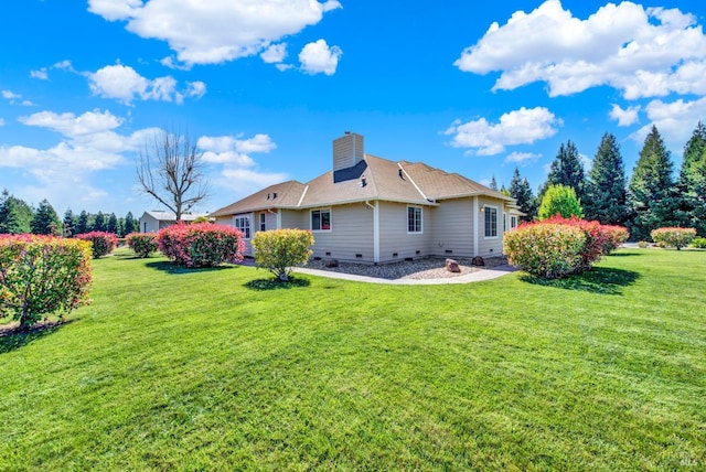 rear view of property featuring a chimney and a yard