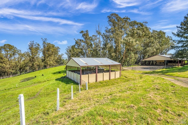view of yard with an enclosed area, an outdoor structure, a rural view, and an exterior structure