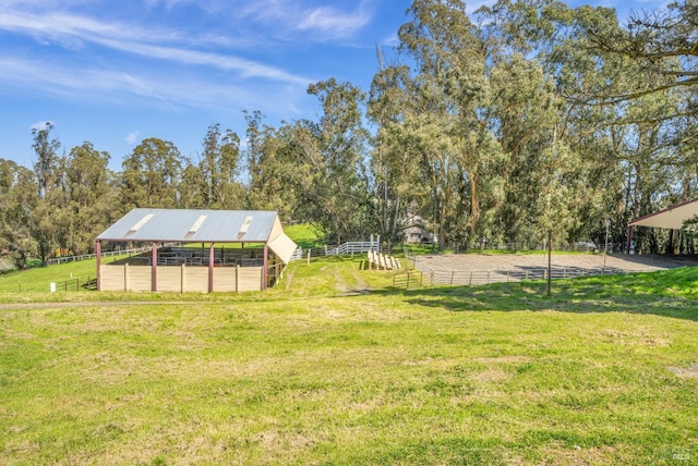 view of yard featuring an exterior structure, an enclosed area, an outdoor structure, and a rural view