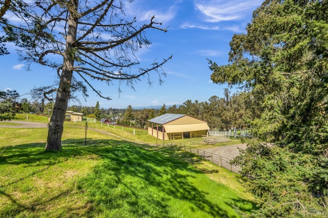 view of yard featuring an outbuilding, a rural view, and an exterior structure