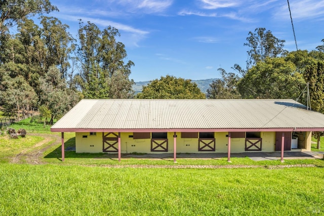 view of front facade with concrete block siding, metal roof, an outbuilding, and an exterior structure
