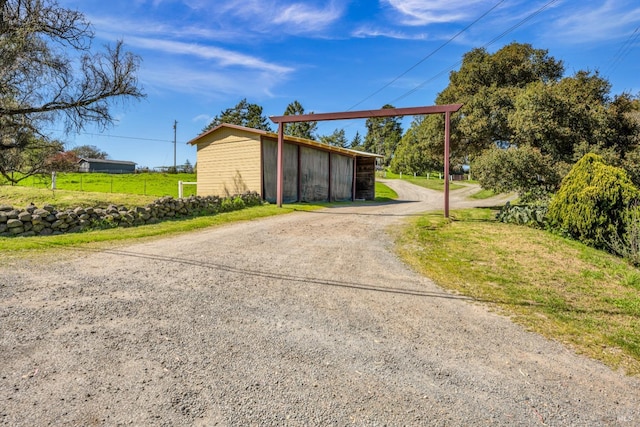 view of outbuilding with driveway and fence